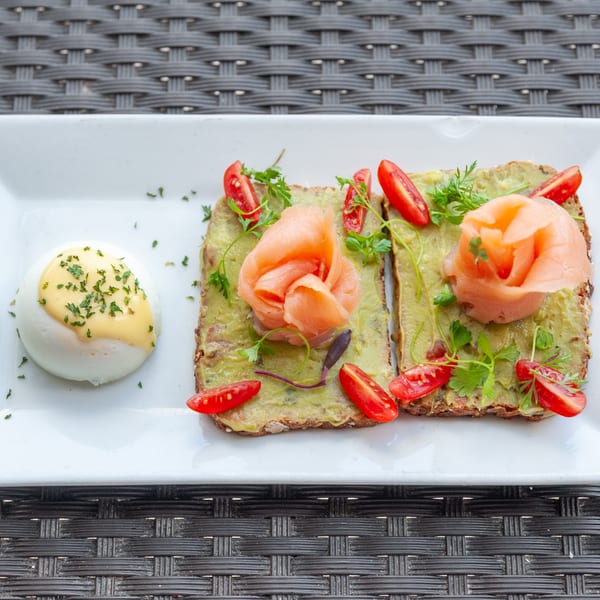 Avocado toast with smoked salmon, cherry tomatoes, and a poached egg with hollandaise sauce.