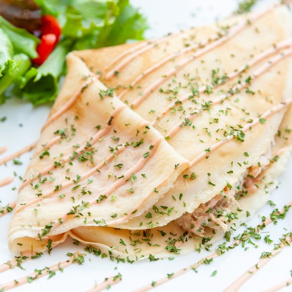 Savory French crepe drizzled with sauce and herbs, served with a side salad.